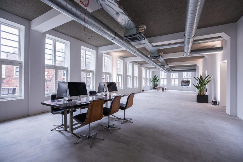 Modern, licht kantoorinterieur aan de Prins Hendrikkade met werkplekken, grote ramen en industriële details.